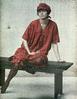 Young woman posing on bench wearing red dress and red bonnet