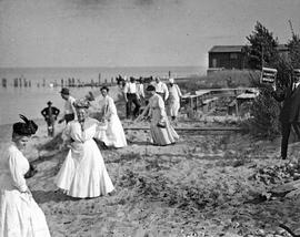 Beach event -- Women in hats, man displaying box of Kennedy's Biscuits