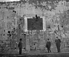 Three men in front of wrought iron gate with angel relief